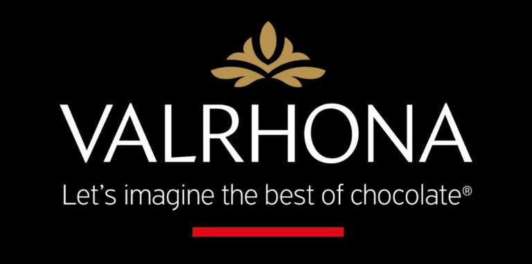 Hier sieht man das Valrhona Logo mit dem Claim Lets imagine the best of chocolat, in weißer Schrift auf schwarzem Hintergrund. Darunter ist ein roter Strich platziert, oben drüber eine florale Grafik in gold.